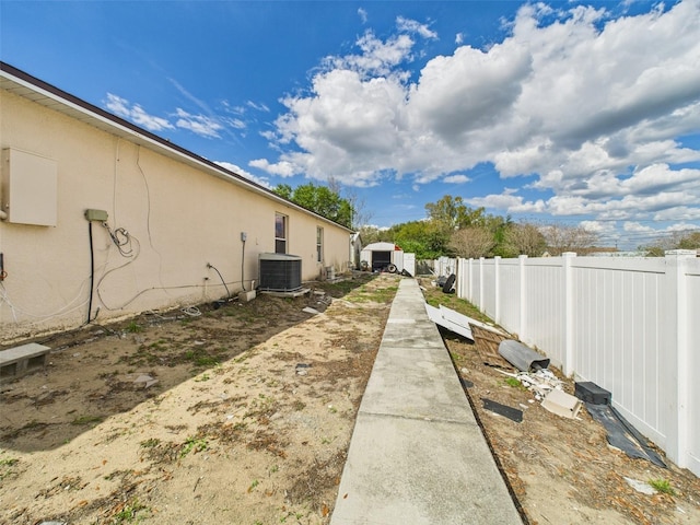 view of yard featuring fence and central air condition unit