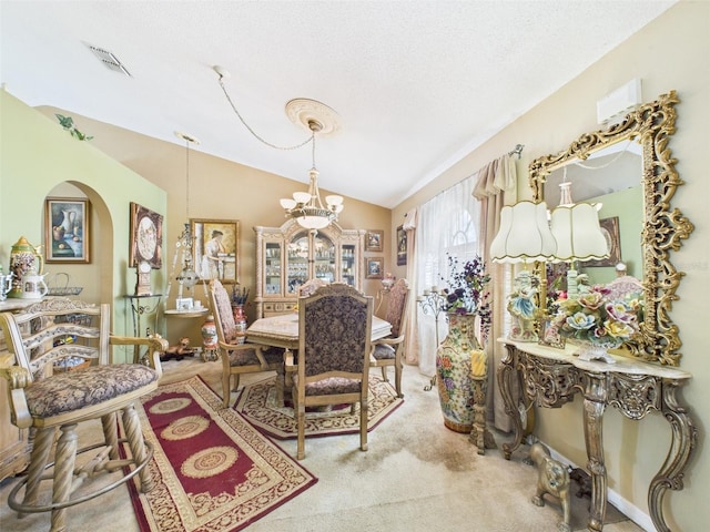 carpeted dining room with visible vents, arched walkways, lofted ceiling, a textured ceiling, and a chandelier