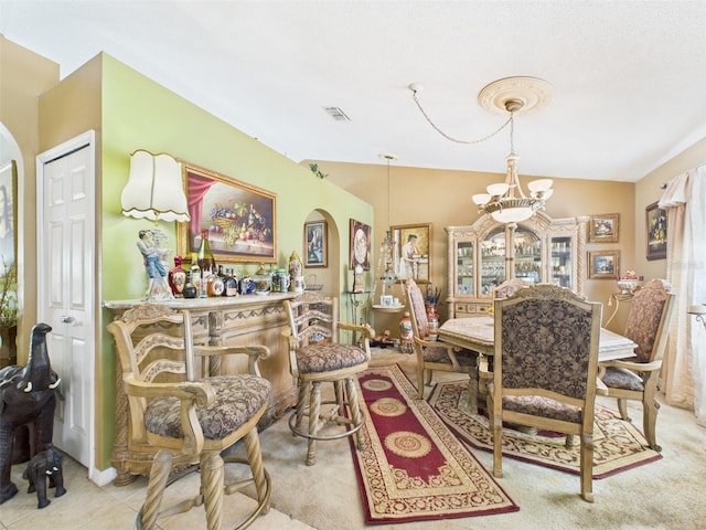 dining space featuring arched walkways, a chandelier, tile patterned flooring, visible vents, and vaulted ceiling