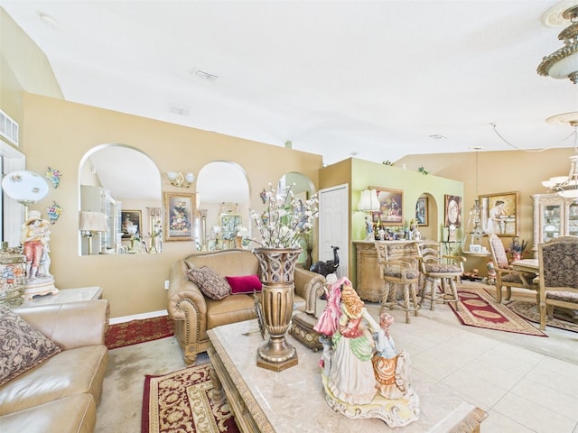 living area with baseboards, visible vents, lofted ceiling, a notable chandelier, and light tile patterned flooring