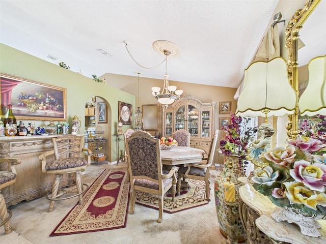 carpeted dining room featuring lofted ceiling, visible vents, arched walkways, and an inviting chandelier