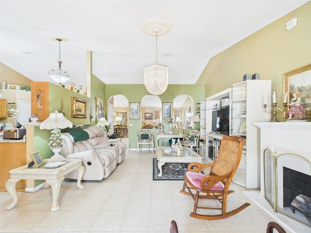 living room with arched walkways, a fireplace with raised hearth, light tile patterned floors, and vaulted ceiling