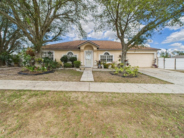 ranch-style home featuring a garage, fence, driveway, stucco siding, and a front yard