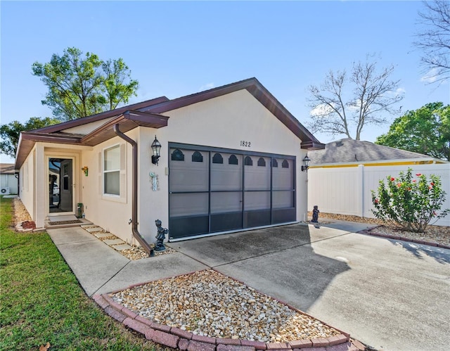 view of front of property featuring driveway, an attached garage, fence, and stucco siding