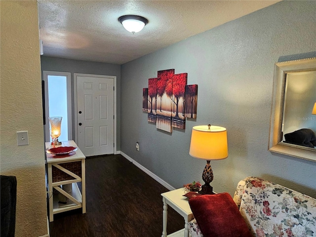 entryway with a textured ceiling, baseboards, wood finished floors, and a textured wall