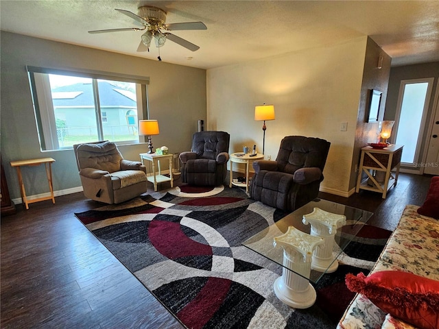 living area with a ceiling fan, a textured ceiling, baseboards, and wood finished floors