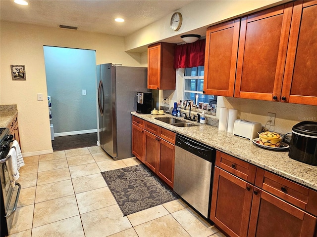 kitchen featuring light stone counters, visible vents, appliances with stainless steel finishes, a sink, and baseboards