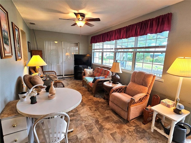 living area featuring a ceiling fan, stone finish flooring, and visible vents