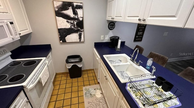 kitchen featuring light tile patterned flooring, white appliances, a sink, white cabinetry, and baseboards