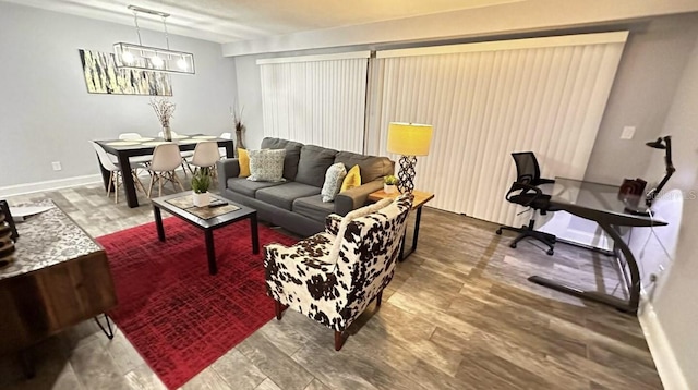 living room featuring baseboards, a chandelier, and wood finished floors