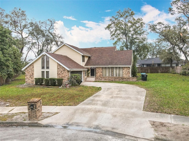 mid-century home featuring brick siding, roof with shingles, a front yard, fence, and driveway