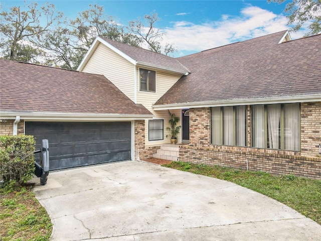 view of front facade featuring an attached garage, driveway, brick siding, and a shingled roof