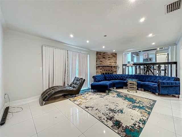 living area with a textured ceiling, recessed lighting, visible vents, a brick fireplace, and tile patterned floors