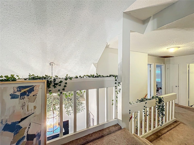 corridor featuring a textured ceiling and an upstairs landing