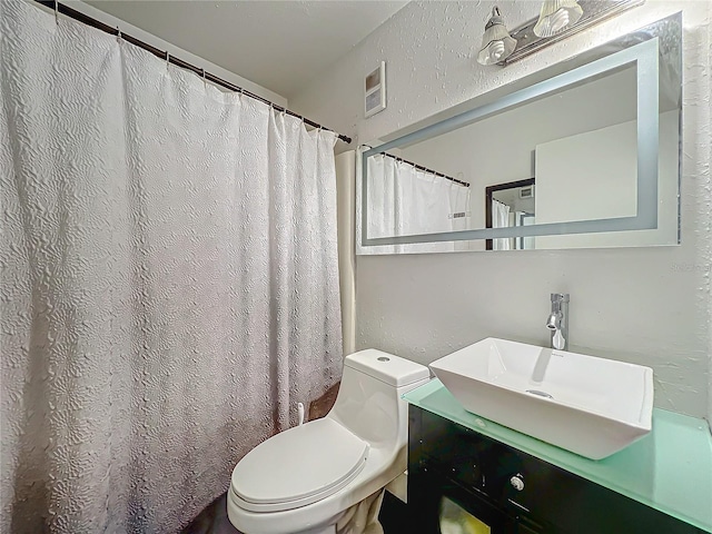 bathroom with visible vents, a textured wall, vanity, and toilet