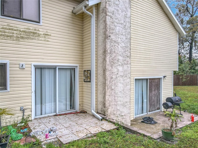 view of exterior entry featuring a patio and fence