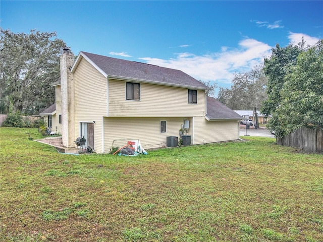 back of house with a chimney, fence, a lawn, and central AC