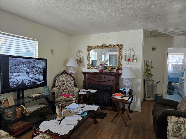 living room featuring a textured ceiling, a fireplace, wood finished floors, and a wealth of natural light