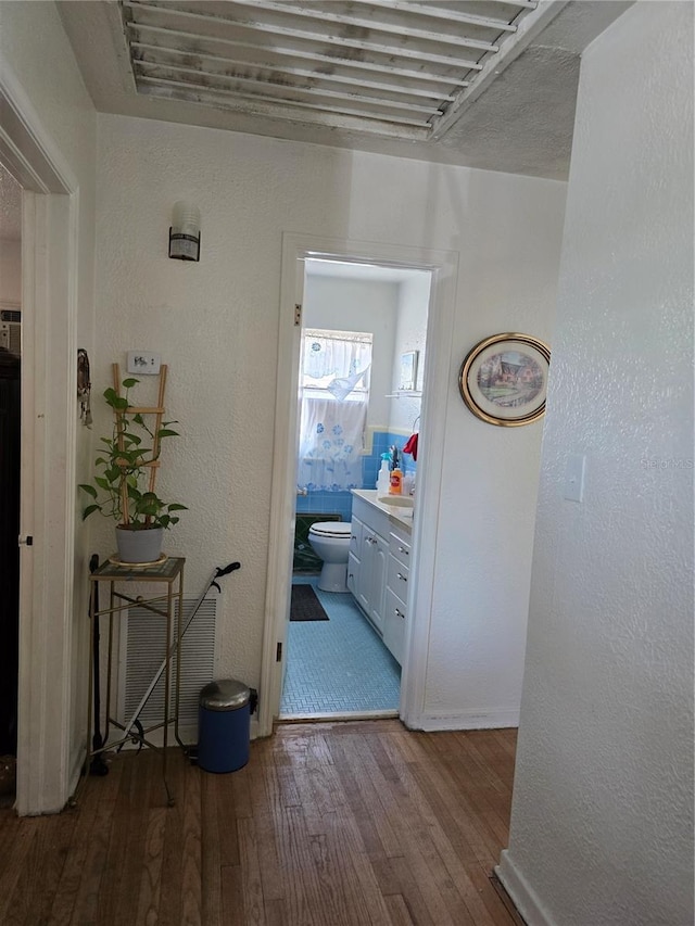 corridor with a textured wall and hardwood / wood-style flooring