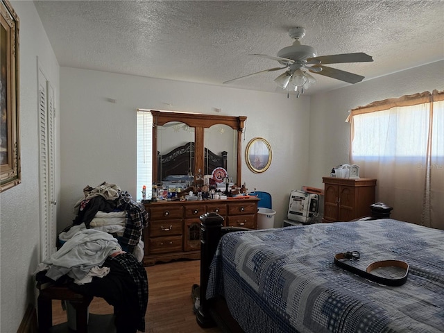 bedroom featuring a textured ceiling, multiple windows, wood finished floors, and a ceiling fan