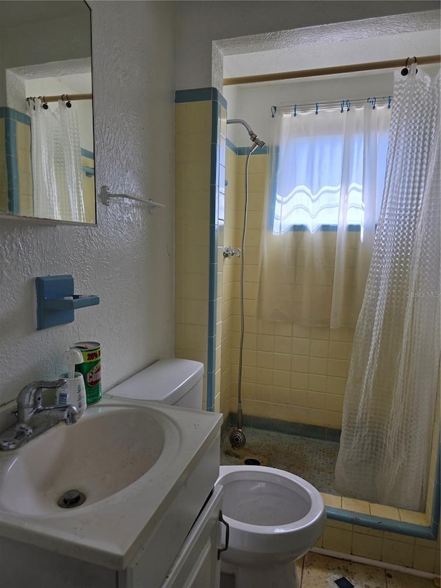 full bathroom featuring a stall shower, a textured wall, vanity, and toilet