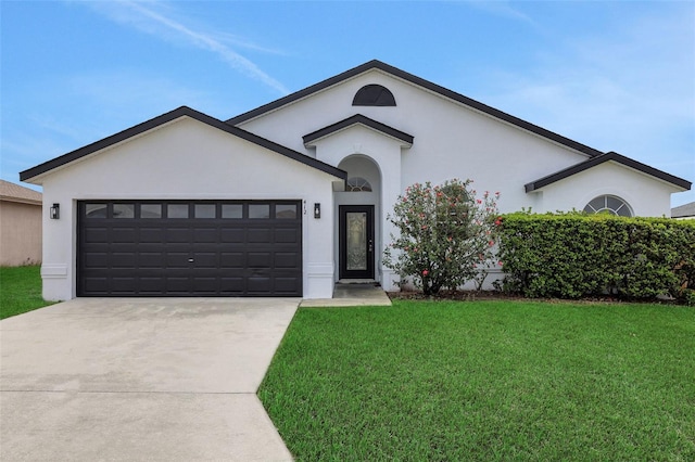 ranch-style home with concrete driveway, a front lawn, an attached garage, and stucco siding