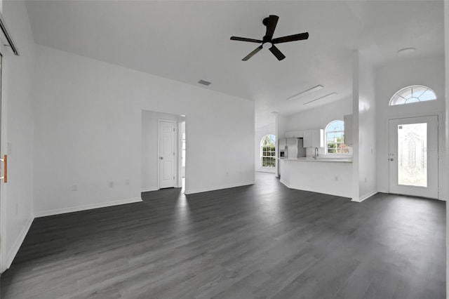 unfurnished living room with ceiling fan, a sink, visible vents, baseboards, and dark wood finished floors