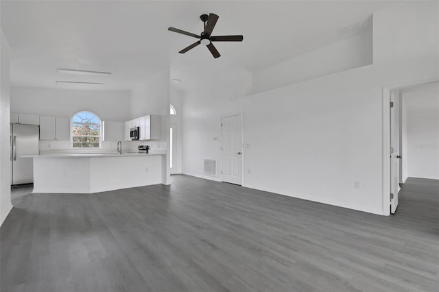 unfurnished living room featuring dark wood-style floors, visible vents, ceiling fan, a sink, and baseboards