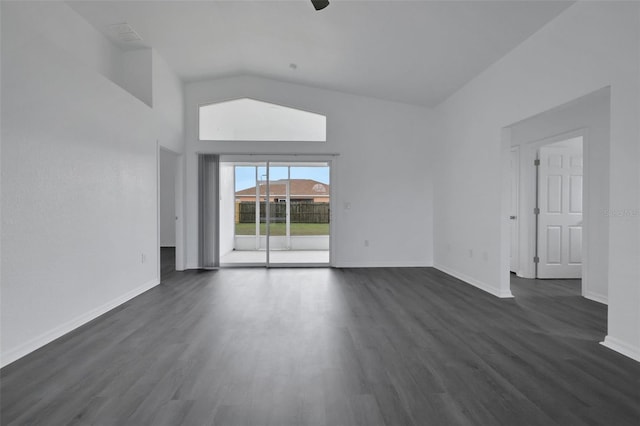 spare room featuring dark wood-type flooring, lofted ceiling, and baseboards