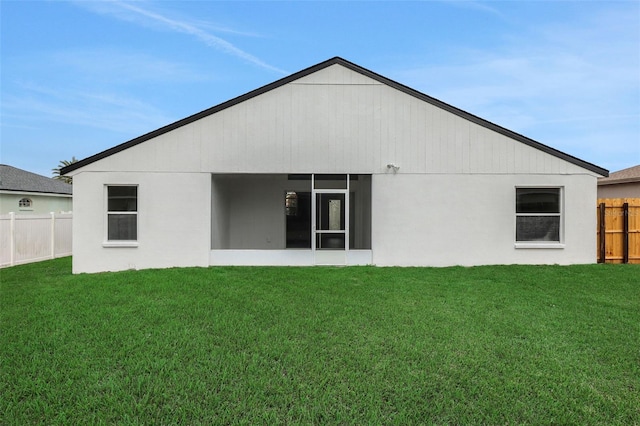 back of house featuring a yard, fence, and a sunroom