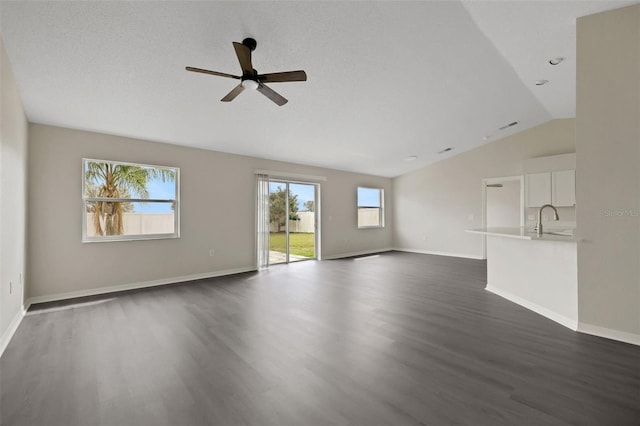 unfurnished living room with lofted ceiling, baseboards, dark wood-type flooring, and a sink