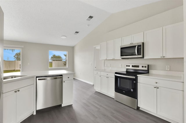 kitchen with lofted ceiling, light countertops, visible vents, appliances with stainless steel finishes, and white cabinets