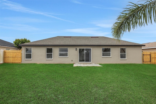 rear view of house featuring roof with shingles, a fenced backyard, a yard, and stucco siding