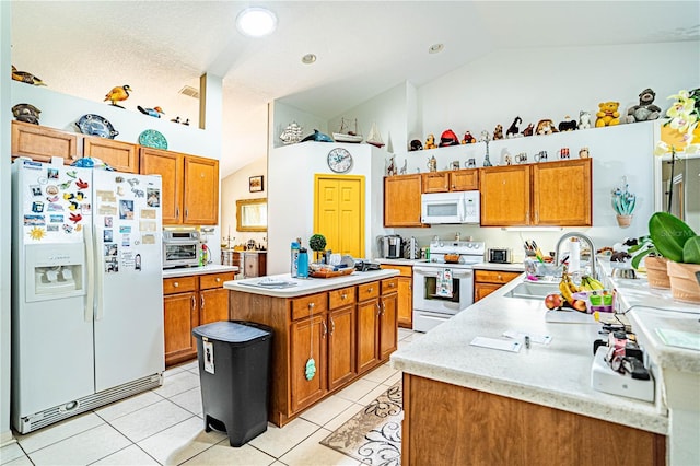 kitchen with light countertops, white appliances, light tile patterned flooring, and brown cabinets