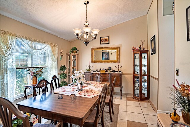 dining space featuring light tile patterned floors, a chandelier, a textured ceiling, baseboards, and vaulted ceiling