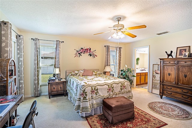 bedroom featuring light carpet, a textured ceiling, visible vents, and baseboards