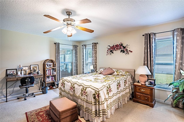 carpeted bedroom featuring ceiling fan, a textured ceiling, and baseboards