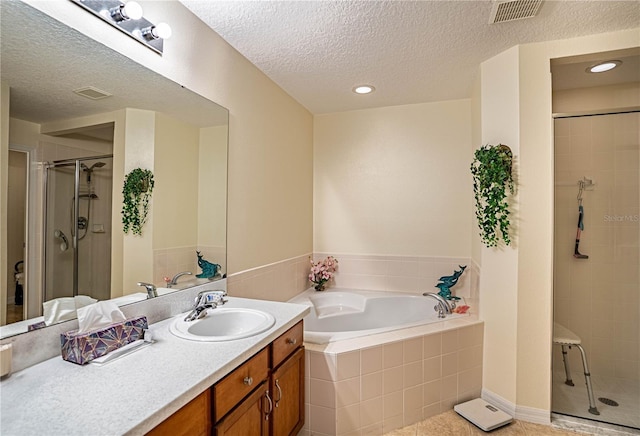 full bathroom featuring visible vents, a stall shower, vanity, a textured ceiling, and a bath