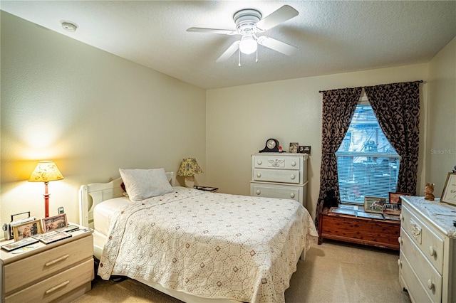 bedroom featuring light carpet, ceiling fan, and a textured ceiling