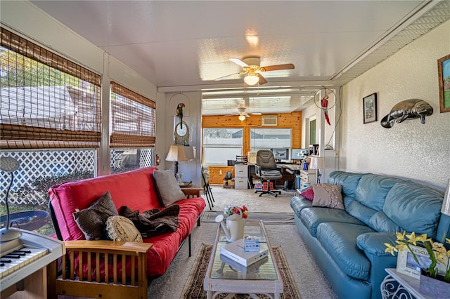 living area with a ceiling fan, carpet flooring, and a textured wall