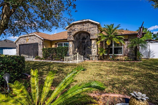 view of front facade with an attached garage, stone siding, fence, and a front yard