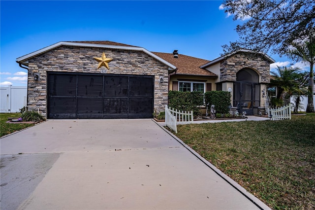 view of front facade with a front yard, fence, a garage, stone siding, and driveway