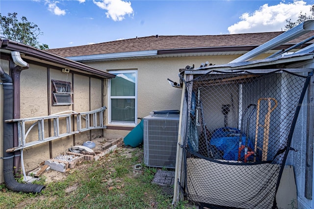 view of property exterior featuring a shingled roof, cooling unit, and stucco siding