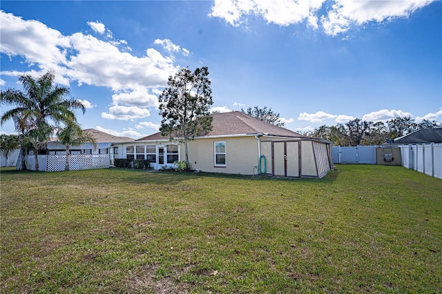 rear view of property with a lawn, a fenced backyard, and stucco siding