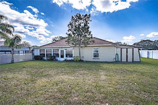 back of property featuring a lawn, fence, and stucco siding