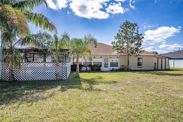 back of property featuring a storage shed, a lawn, an outbuilding, fence, and stucco siding