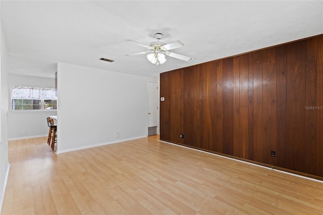 unfurnished room with baseboards, a ceiling fan, visible vents, and light wood-style floors