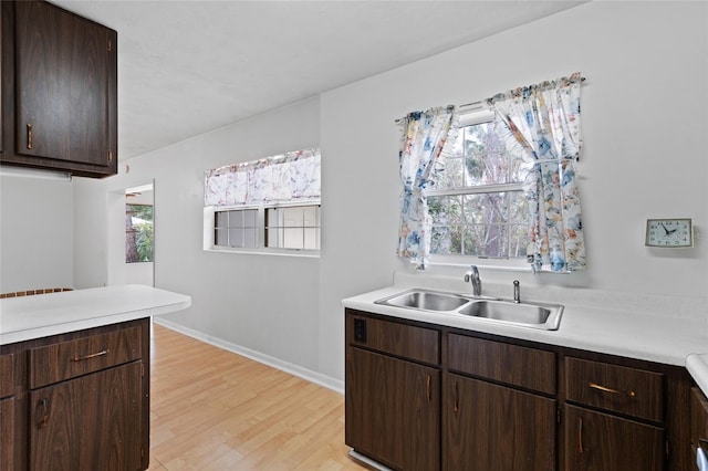 kitchen featuring light wood finished floors, light countertops, and a sink