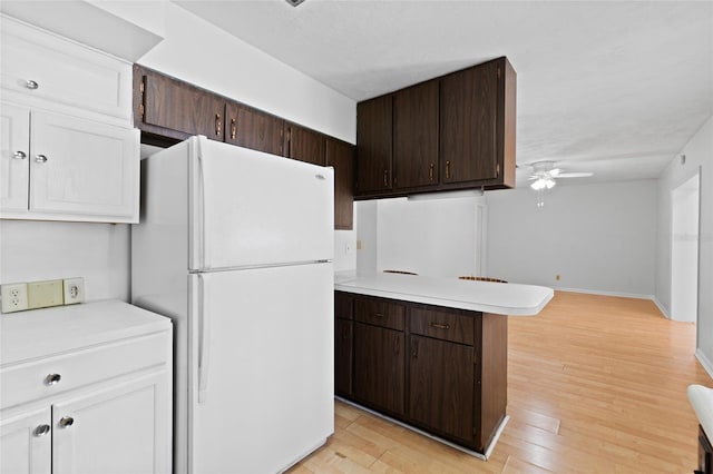 kitchen with light countertops, freestanding refrigerator, and dark brown cabinetry