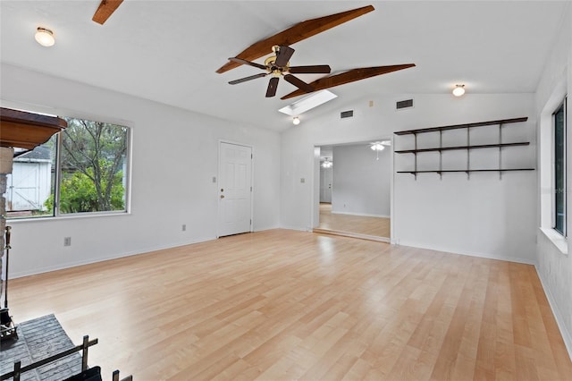 unfurnished living room featuring light wood finished floors, visible vents, lofted ceiling with skylight, ceiling fan, and baseboards